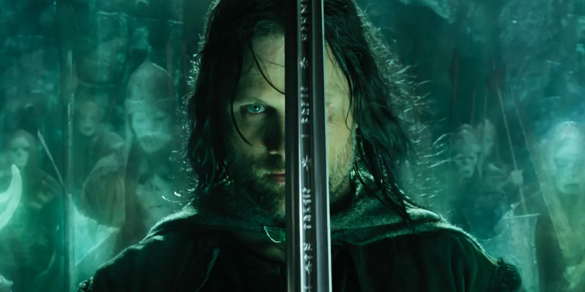 A white man holds a sword in front of his face while looking intensely into the camera in "The Lord of the Rings: The Return of the King"