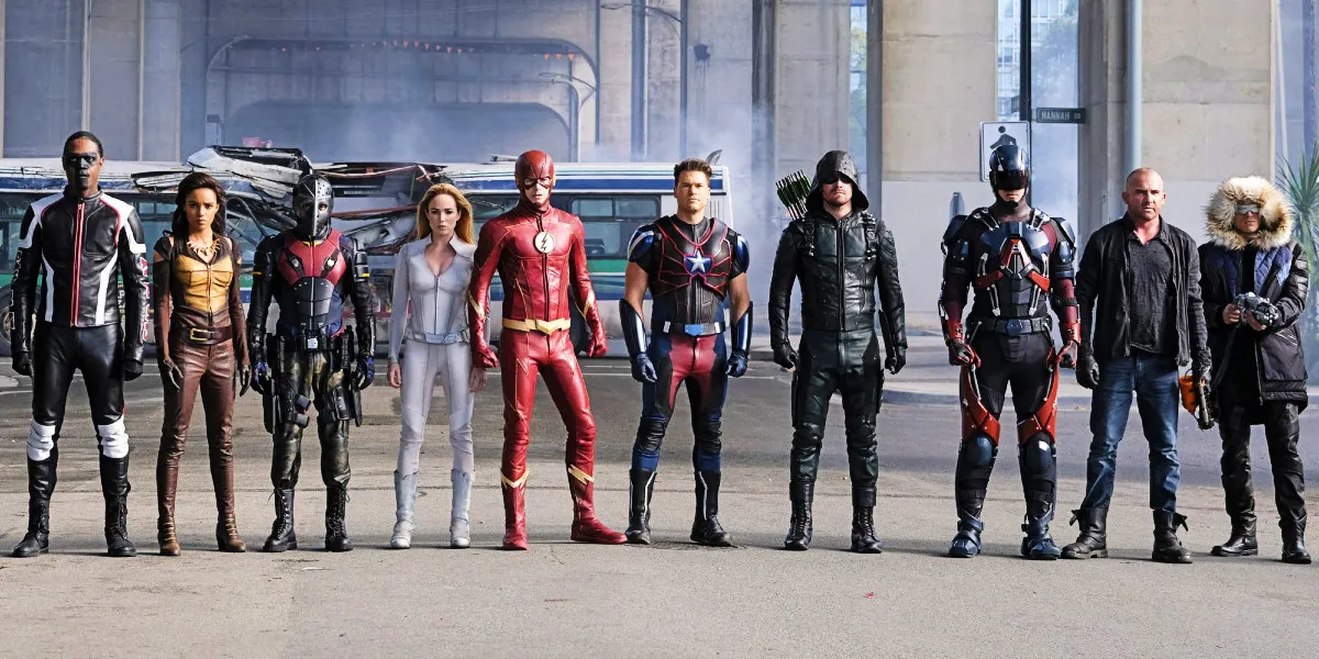 The cast of an Arrowverse Crossover, lined up in a row, includes characters like Mr. Terrific, Sarah Lance, The Flash, Arrow, The Atom and Captain Cold