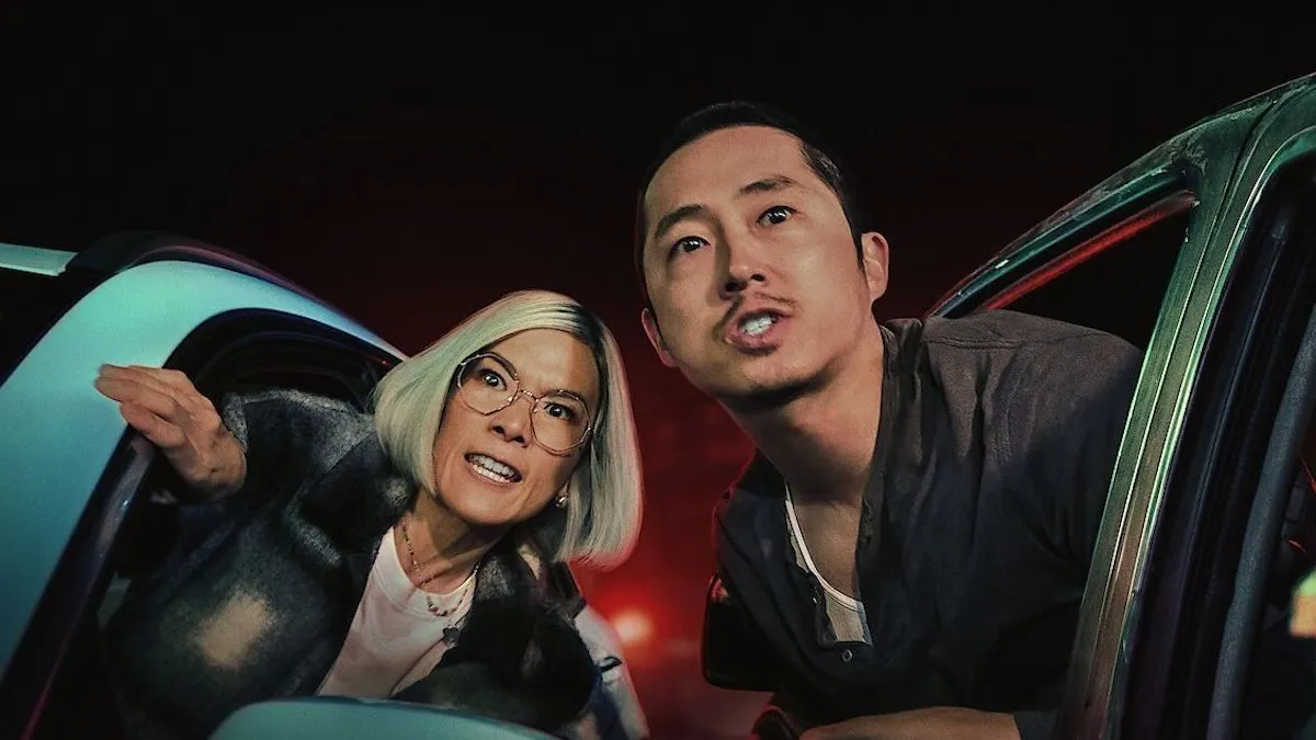 An Asian woman and man lean out the window of their respective cars with vengeful looks on their faces.