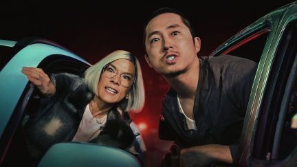An Asian woman and man lean out the window of their respective cars with vengeful looks on their faces.