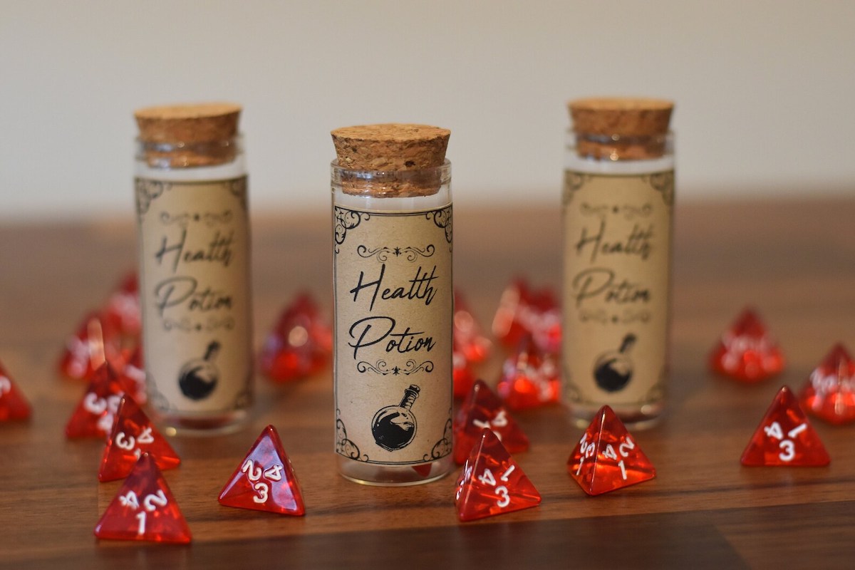 A large number of red pyramidal dice scattered around three glass vials with aged labels saying healing potion on them.