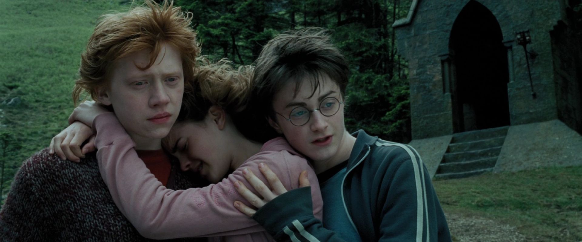 Ron Weasley, Hermione Granger, and Harry Potter stand in a group hug