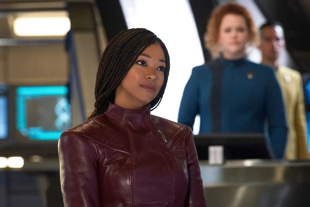 Captain Michael Burnham in 'Star Trek: Discovery': A Black woman with long braids smiles as she looks to the right, wearing an all red star trek uniform.