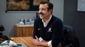 Ted smiling at his desk on Ted Lasso