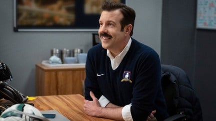 Ted smiling at his desk on Ted Lasso
