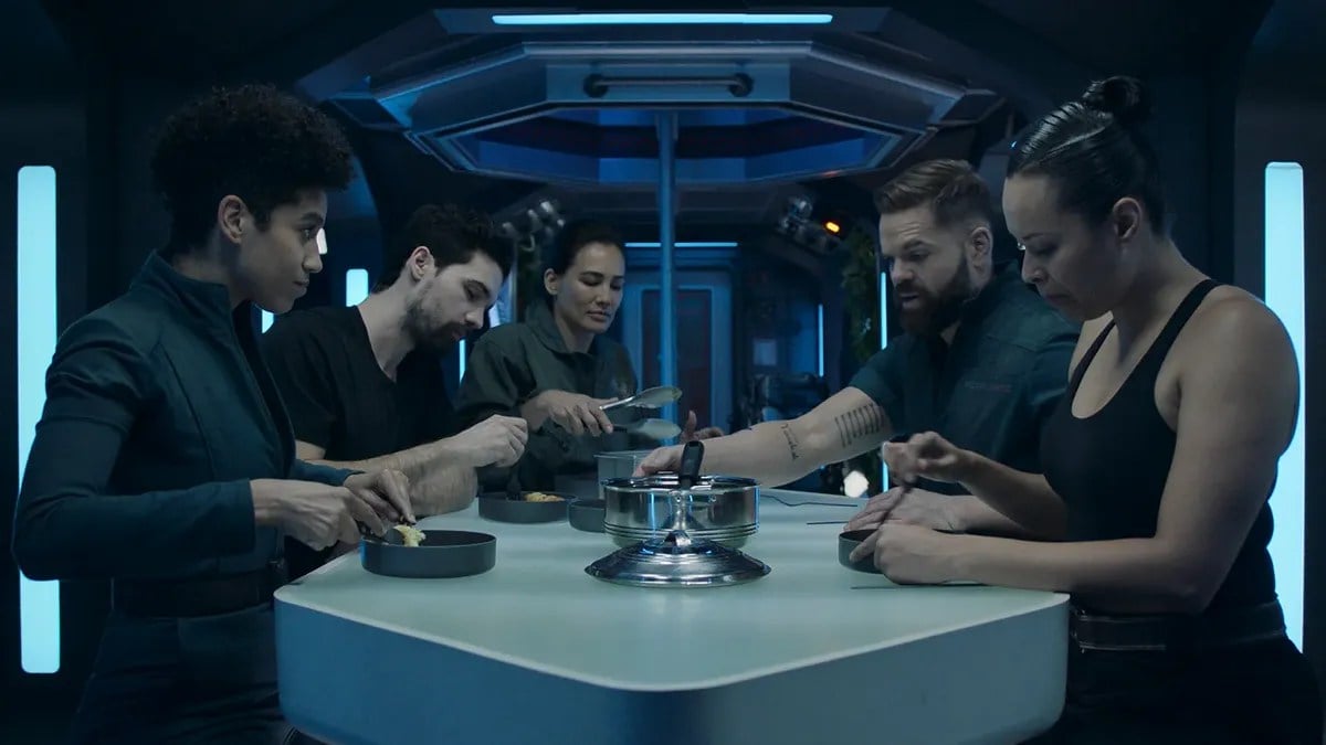 Image of 5 cast members from the Amazon show 'The Expanse.' Three women of color and two white men eating in a spaceship mess hall.