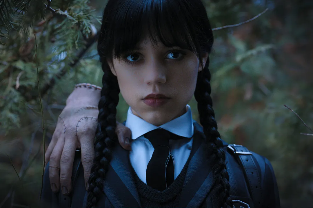 Wednesday Addams stands with Thing on her shoulder