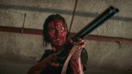 Beth, covered in blood, holds up a shotgun in Evil Dead Rise.