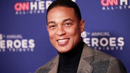 Don Lemon smiles at the camera at an event red carpet, the backdrop behind him reading 