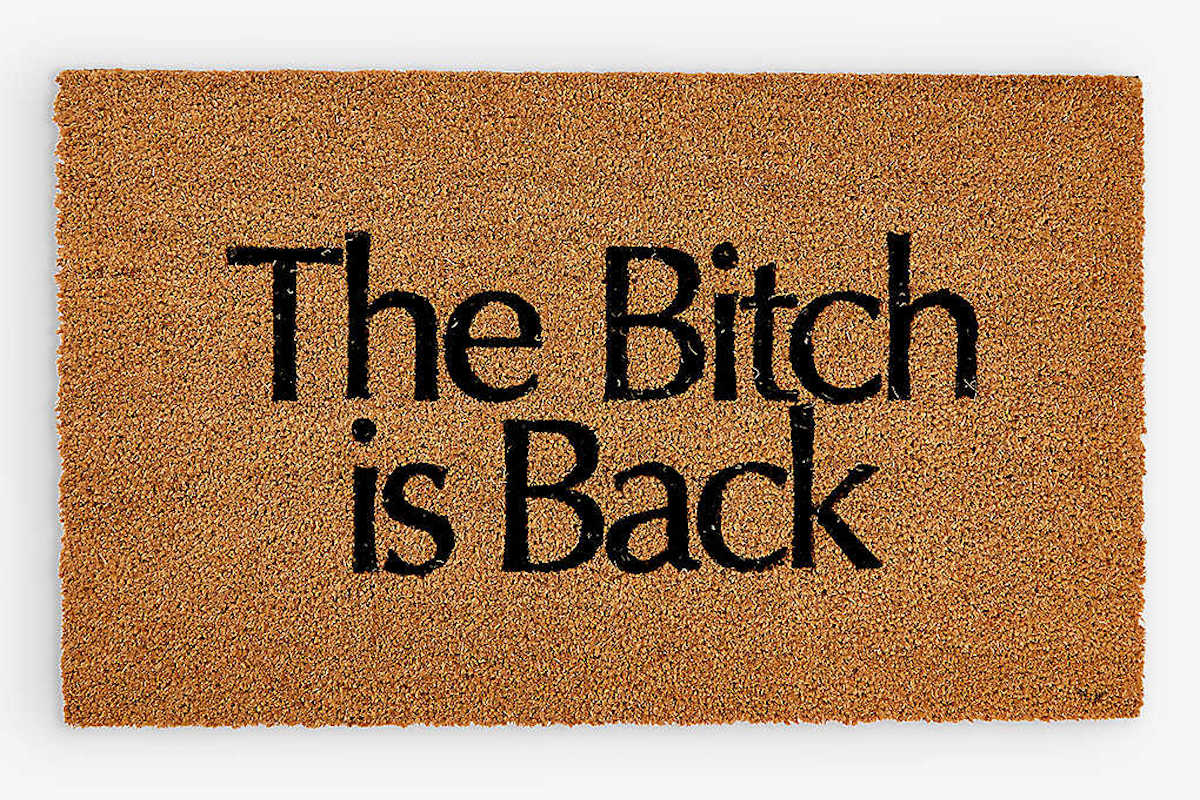 A brown doormat with the words "The bitch is back" on it in black.