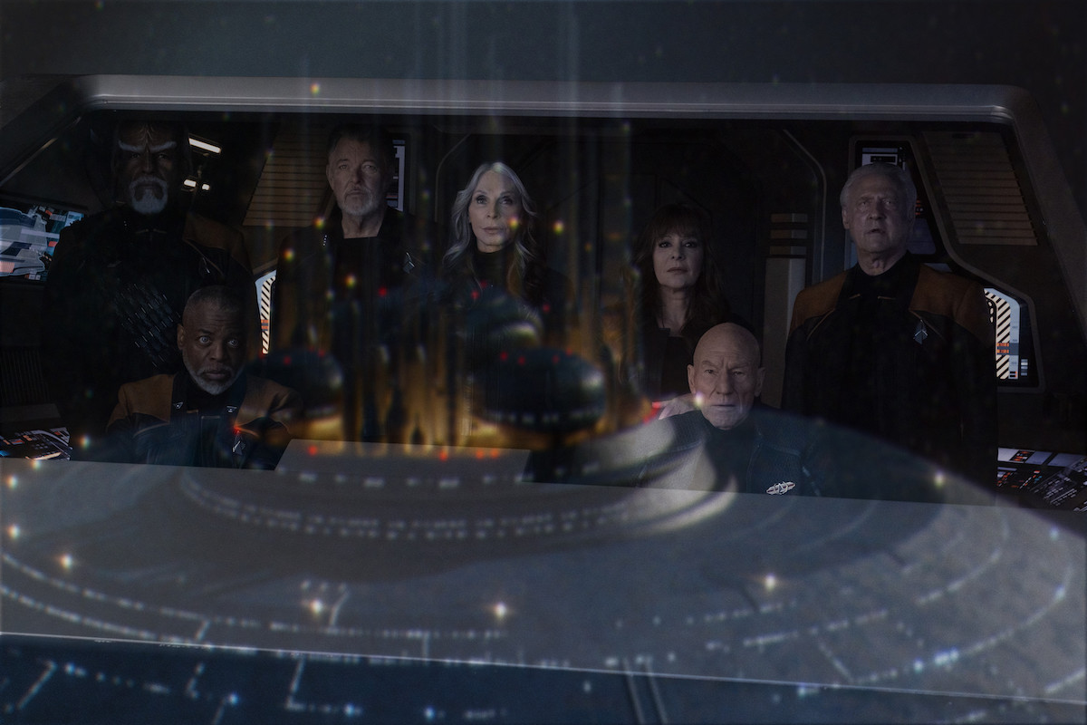 Picard and the rest of his senior officers look out a window at the Enterprise D.