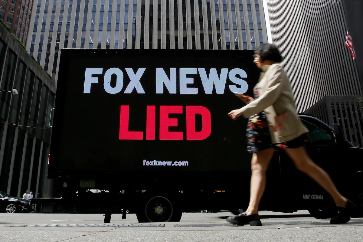 A digital billboard on a city street reads "Fox News lied"
