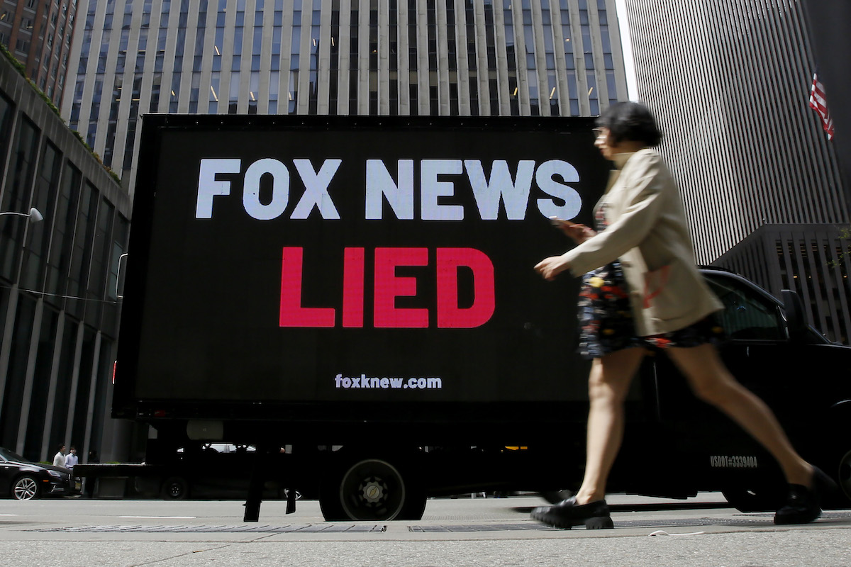 A digital billboard on a city street reads "Fox News lied"