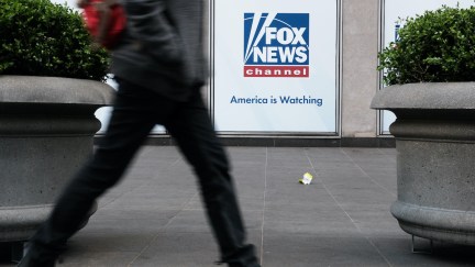 A person seen from the waist down walks by the Fox News office.