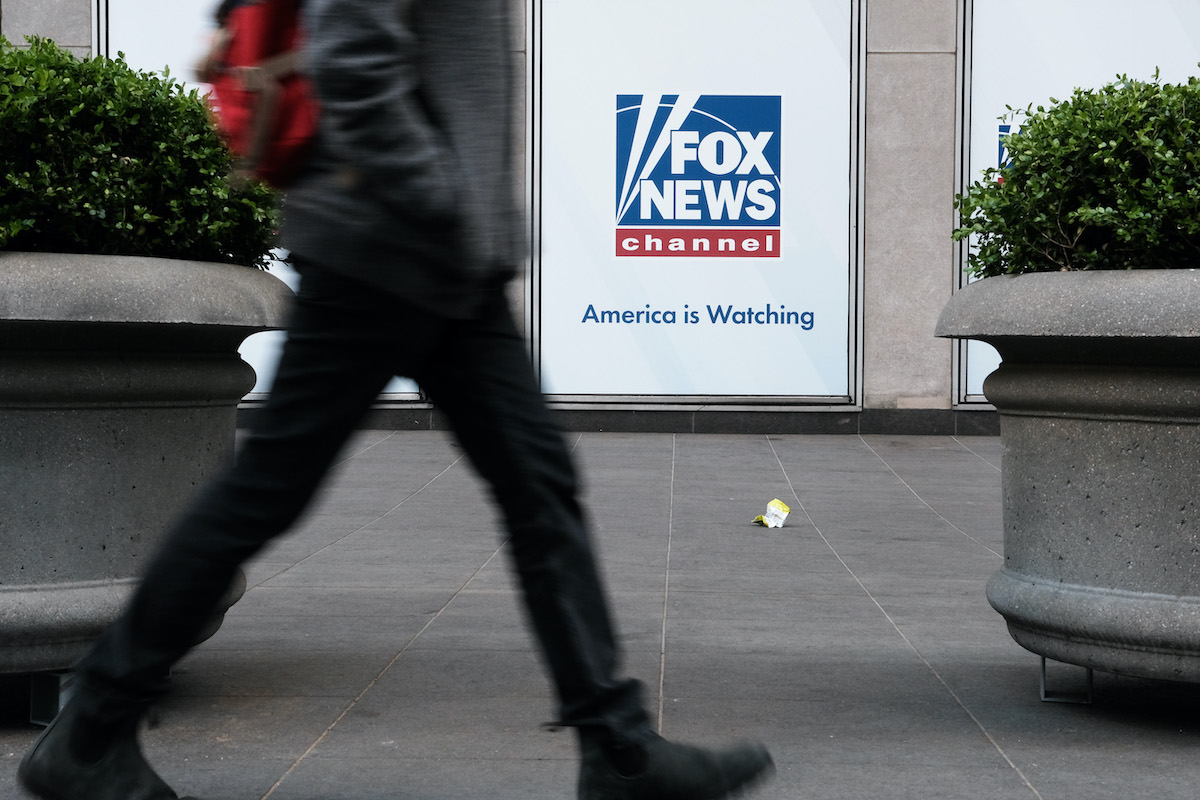 A person seen from the waist down walks by the Fox News office.