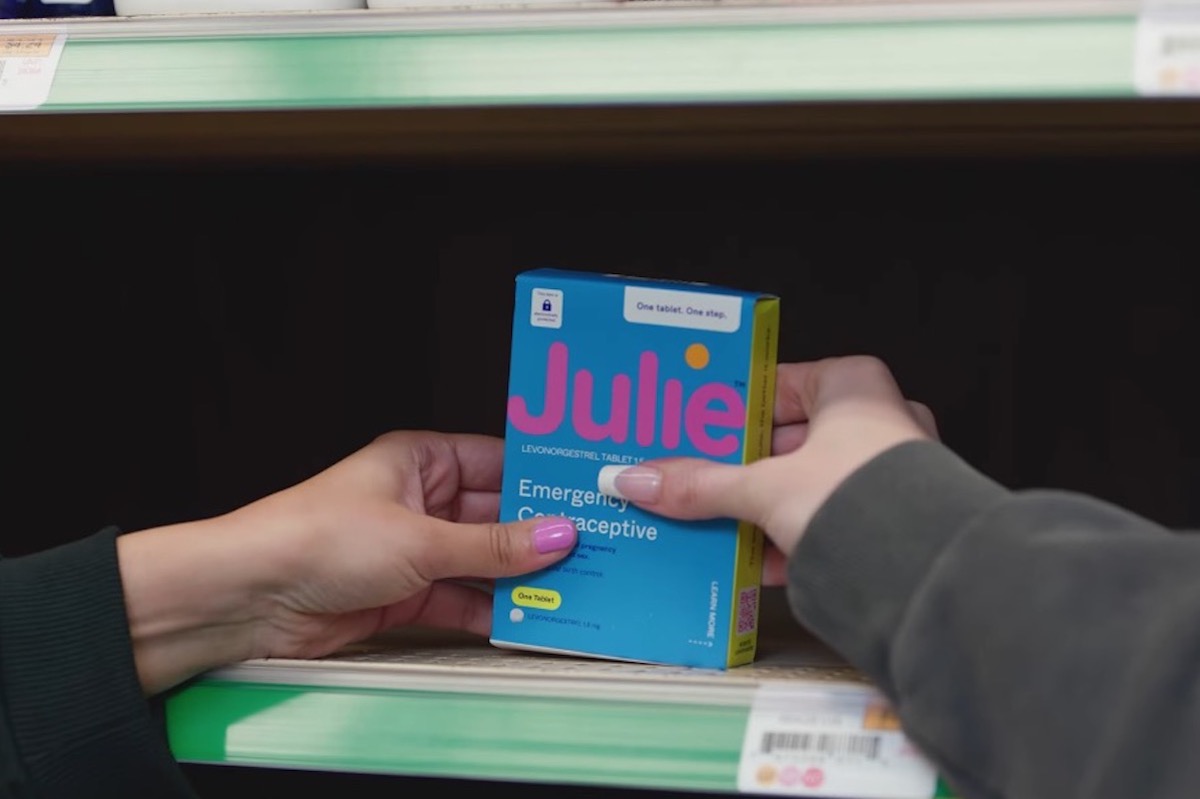 Two hands reach for a box labeled "Julie" sitting on a store shelf.