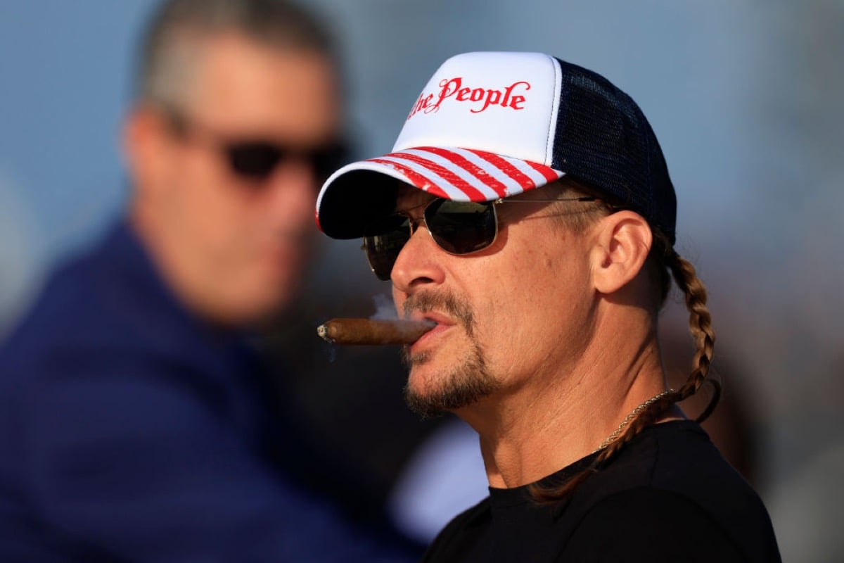 Recording artist Kid Rock smokes a cigar and looks on during the NASCAR Cup Series 64th Annual Daytona 500 at Daytona International Speedway on February 20, 2022 in Daytona Beach, Florida.