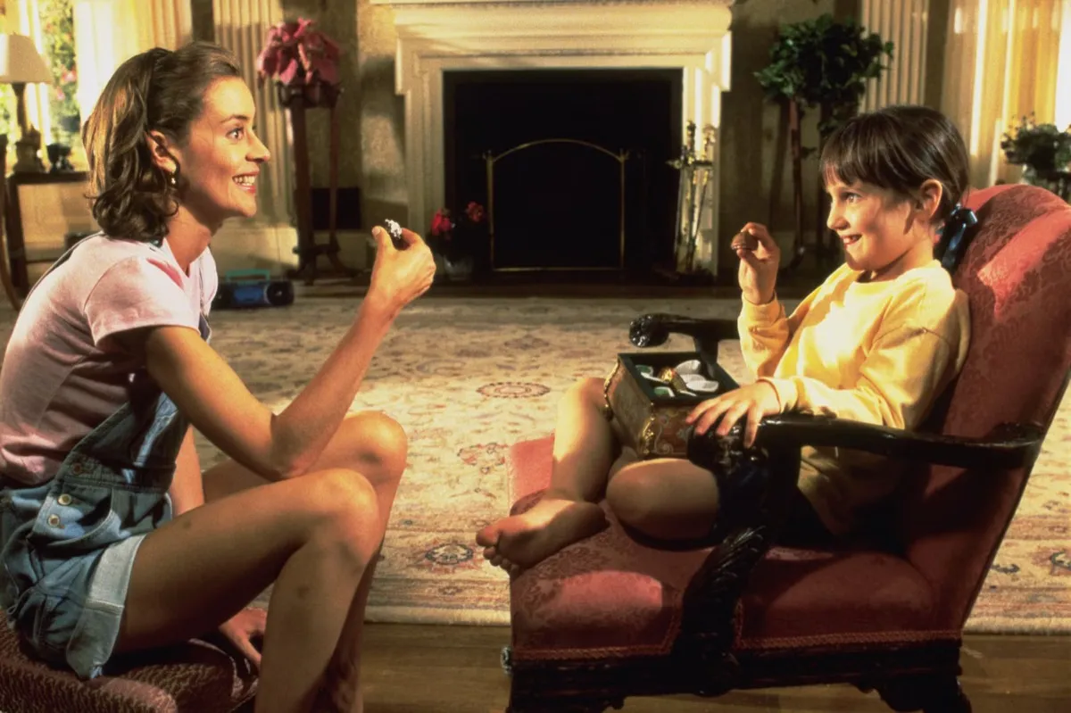 Miss Honey and Matilda smile at each other while sitting in a parlor in "Matilda"