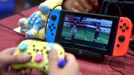 Close up of hands playing a Nintendo Switch via a separate controller.