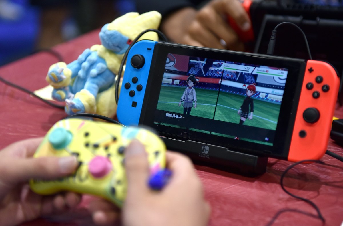 Close up of hands playing a Nintendo Switch via a separate controller.