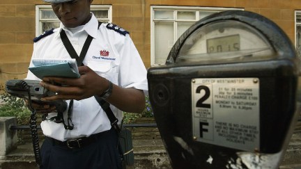 LONDON - JULY 7: A Westminster traffic warden issues a parking ticket on July 7, 2004 in London, England. Money raised in England by parking fines, meters, residential parking schemes and fixed penalty notices has reached almost 1 billion GBP a year, with London motorists contributing almost half of the total.