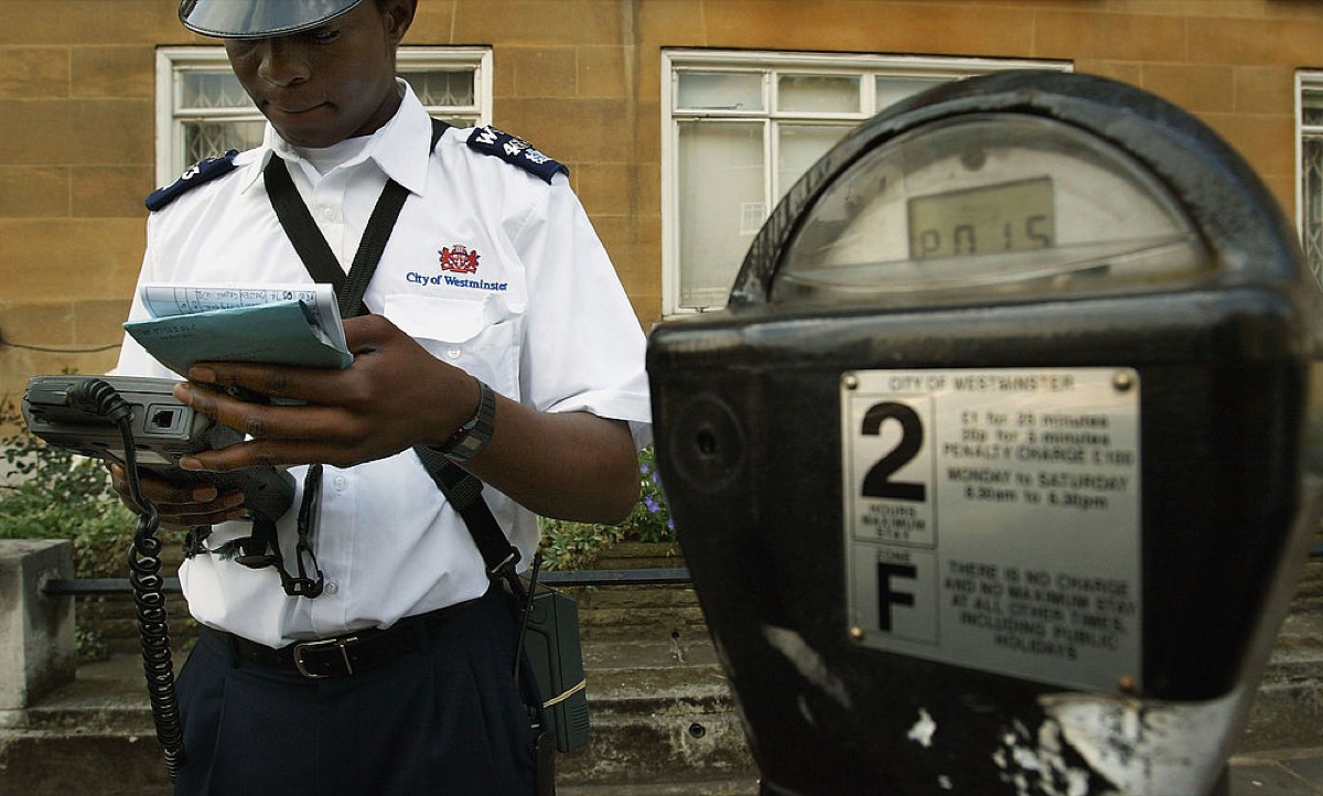LONDON - JULY 7:  A Westminster traffic warden issues a parking ticket on July 7, 2004 in London, England. Money raised in England by parking fines, meters, residential parking schemes and fixed penalty notices has reached almost 1 billion GBP a year, with London motorists contributing almost half of the total.