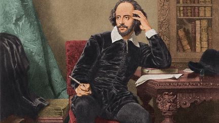A painting of Shakespeare sitting at a desk, holding a quill, thinking.
