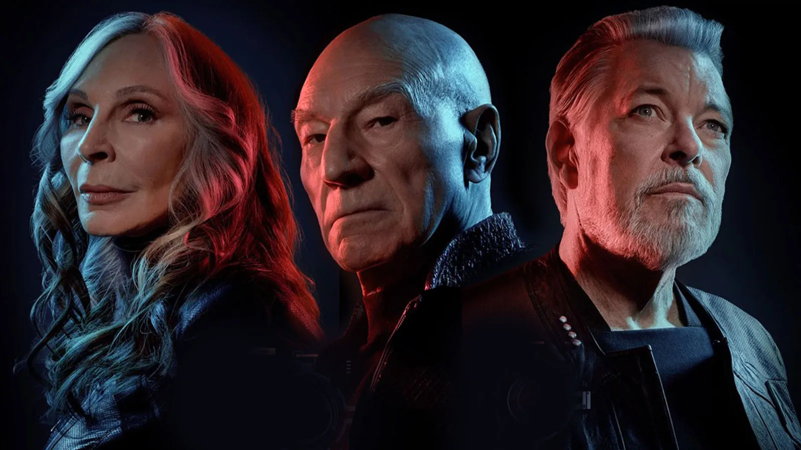 Promotional image for 'Star Trek: Picard' featuring (l-r) Gates McFadden as Beverly Crusher, Patrick Stewart as Jean-luc Picard, and Jonathan Frakes as William Riker. We see them from the shoulders up and they are against a black background. They are Photoshopped together with Crusher and Riker standing with their backs to Picard, who stands at an angle, but faces the camera. Crusher is a white woman with long red hair that has thick white streaks in it. She wears all black. Picard is a bald white man also in all black. Riker is a white man with silver hair an da silver beard. He wears a black jacket over a navy blue shirt. 