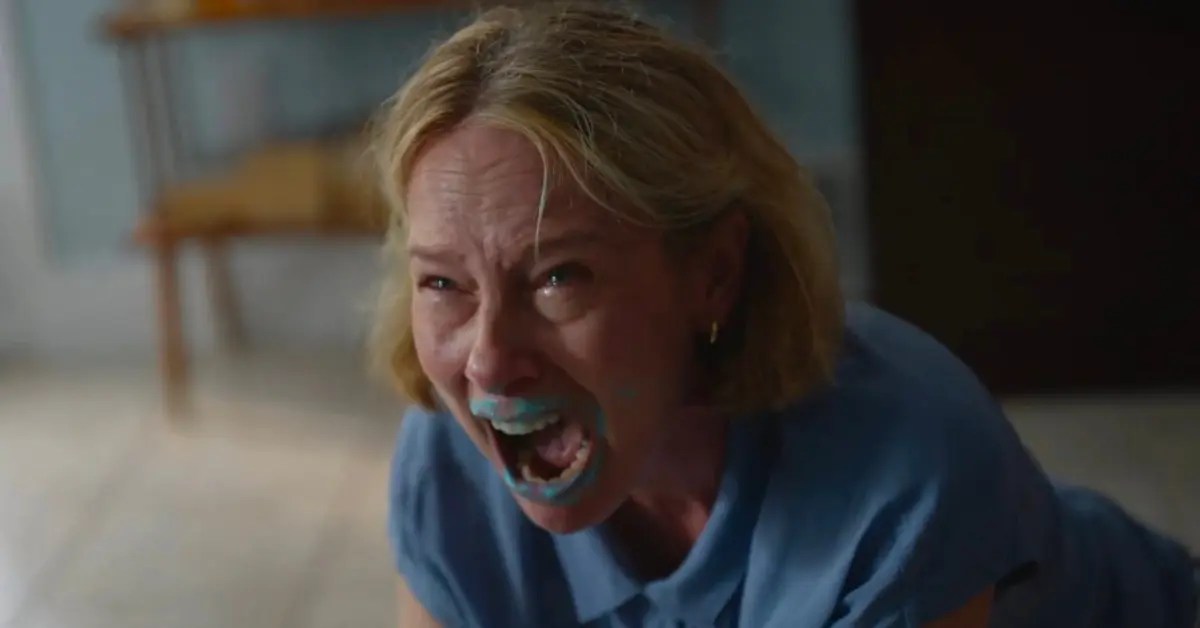 Grace screams in anger, with blue paint on her mouth, while kneeling on the floor. Still from Beau is Afraid.