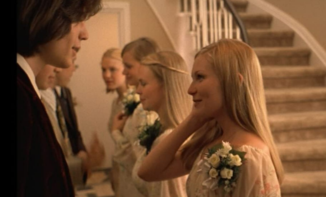 A line of girls dressed in white dresses, looking at boys dressed in suits in The Virgin Suicides.