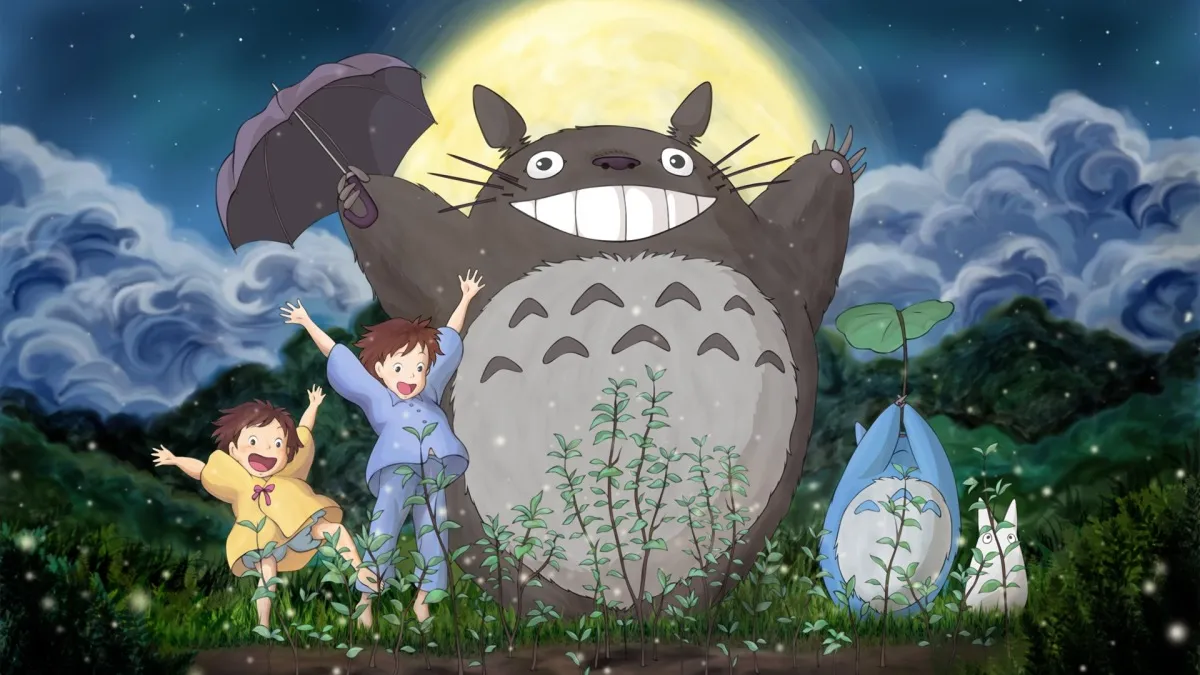 Cuddly monster Totoro celebrates in the moonlight with their babies and two little human girls in "My Neighbor Totoro"