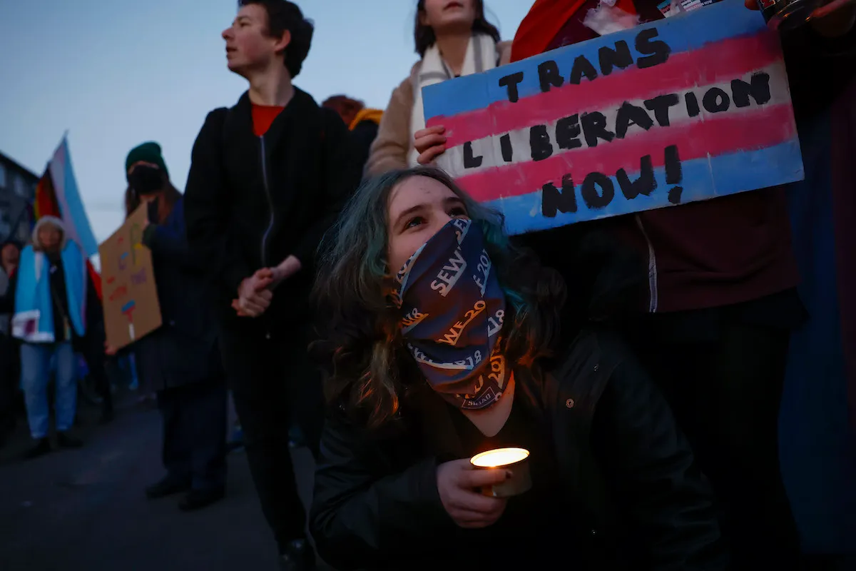 Protesters at a demonstration, holding a sign reading "trans liberation now"