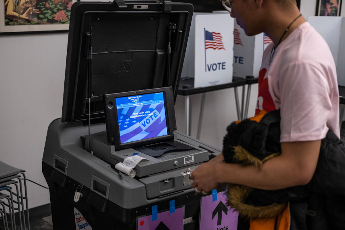 A person stands at a voting machine.