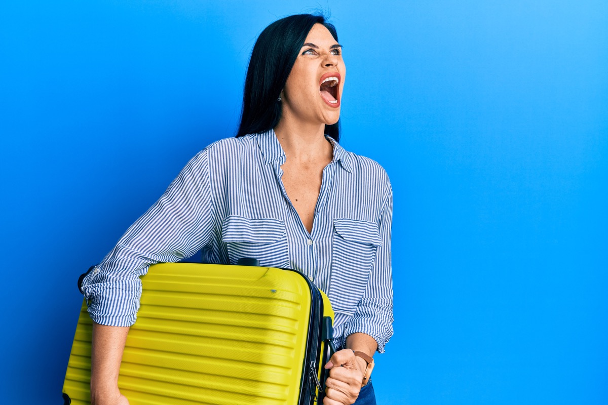 Woman holding luggage and shouting.