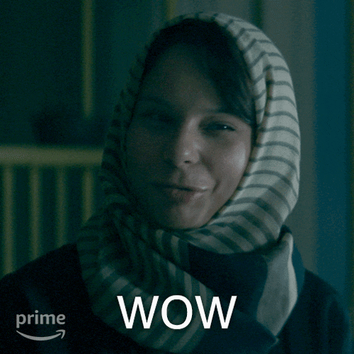 GIF featuring Amina Ben Ismaïl as Nourah in Amazon's 'The Power.' She is a young, light-skinned Saudi Arabian woman wearing a white headscarf with black stripes and a black jacket. Her dark side-bangs are visible at her forehead. She is shaking her head incredulously and saying "Wow," which also appears as text at the bottom of the GIF. The Amazon Prime logo is in the lower left corner.