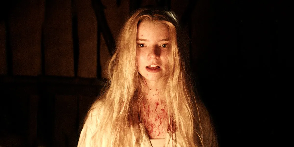 A young woman covered in blood stars into the light of a fire in "The Witch"