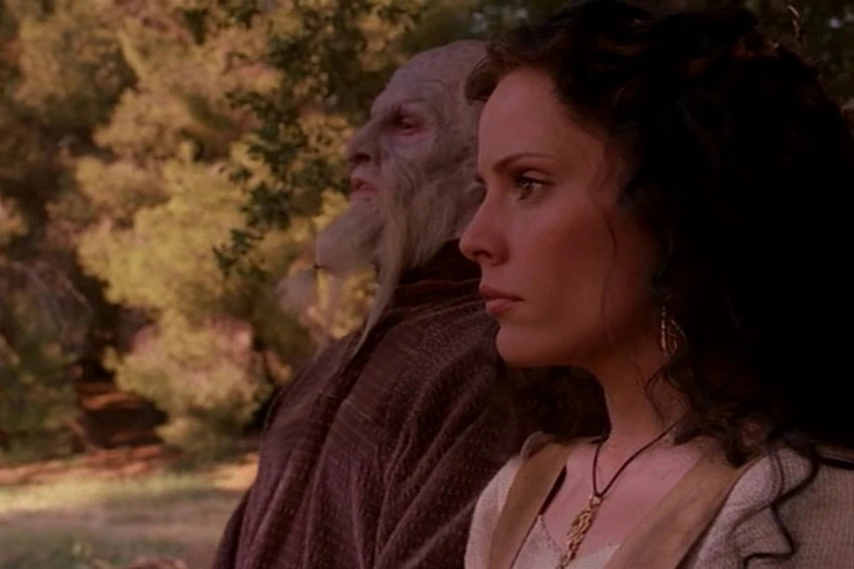 Screenshot from the Buffy episode Selfless; Emma Caulfield Ford as Anya stands next to a pale skinned demon, looking into the distance.