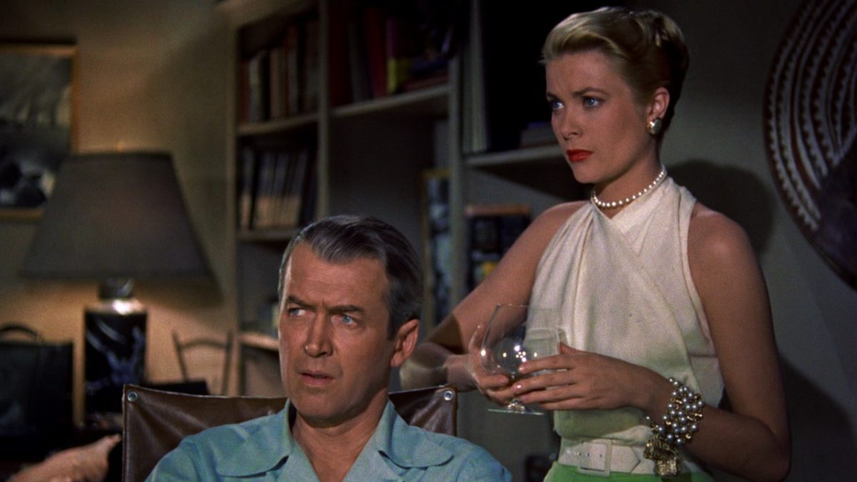 James Stewart and Grace Kelly in 'Rear Window': An elegant woman in a white dress stands behind an older man sitting in a wheelchair.