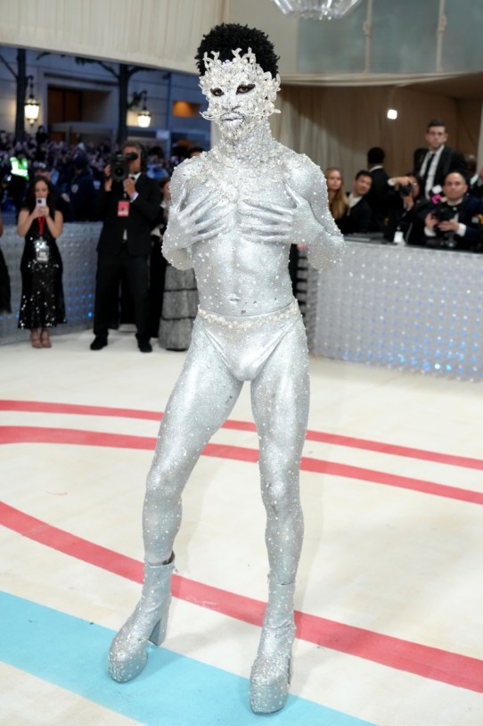 Lil Nas X is pure silver from head to toe, in underwear, boots, masquerade mask, and body paint.
