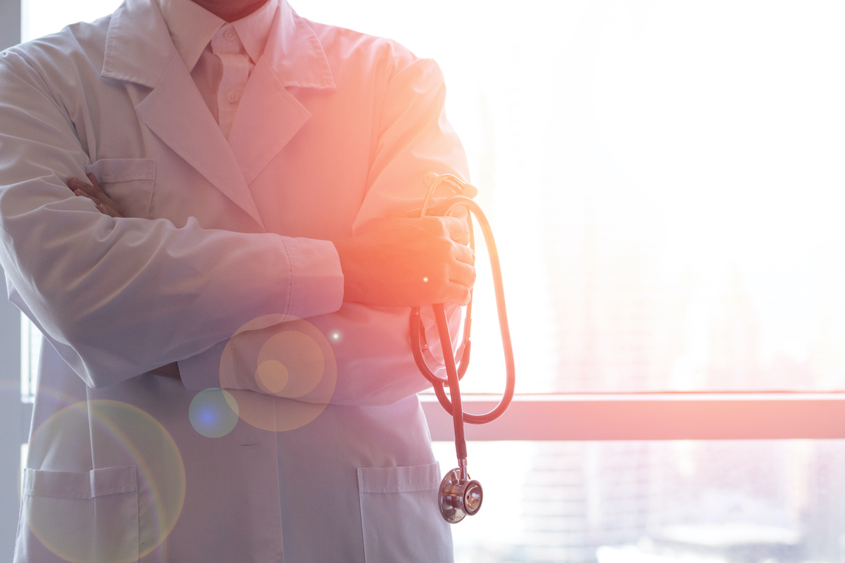 A doctor in a white coat seen from the shoulders down.