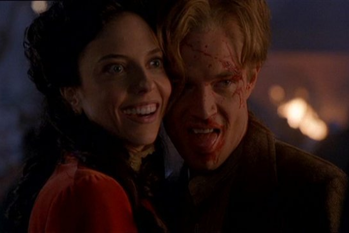 Screenshot from Buffy episode Fool for Love; Juliet Landau as Drusila cuddles up to James Marsters as Spike. He has blood on his face and they're grinning.