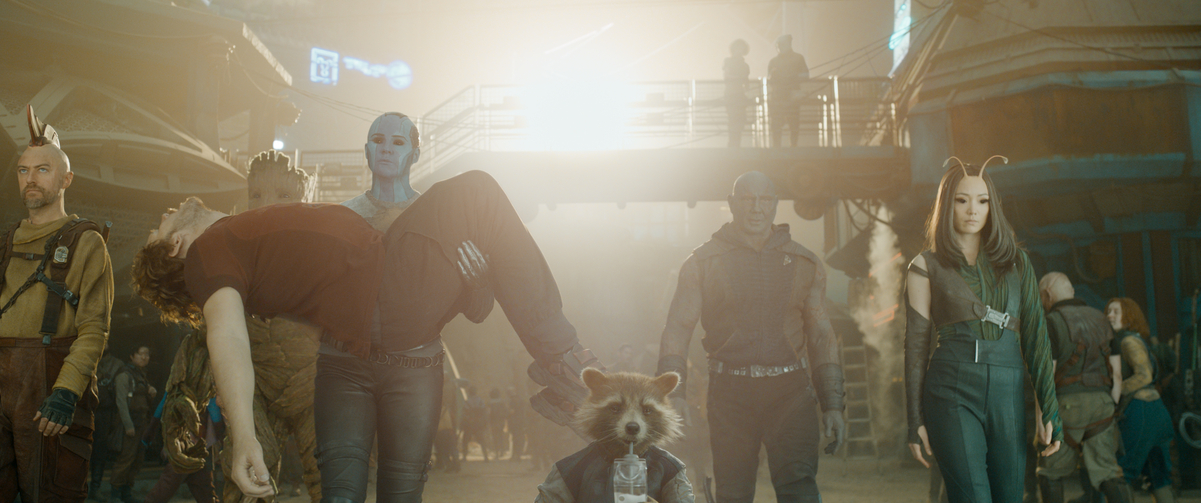 The Guardians of the Galaxy walk toward the camera. Nebula is carrying Peter in her arms.