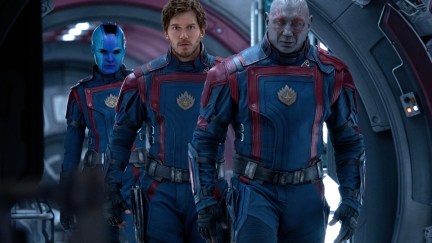Drax, Peter, and Nebula walk down a metal hallway, wearing matching blue and red uniforms.
