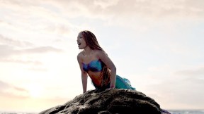Halle Bailey's Ariel sings atop a rock in the ocean in the live-action The Little Mermaid.