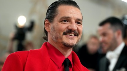 Pedro Pascal smiles in a bright red suit.