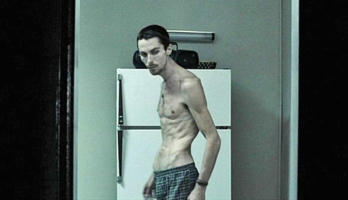An emaciated man stands in his kitchen in "The Machinist"