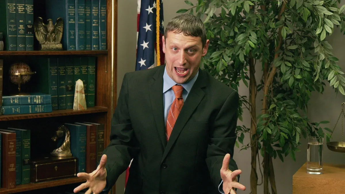 Tim Robinson looks distressed, wearing a suit with an office behind him in 'I Think You Should Leave'