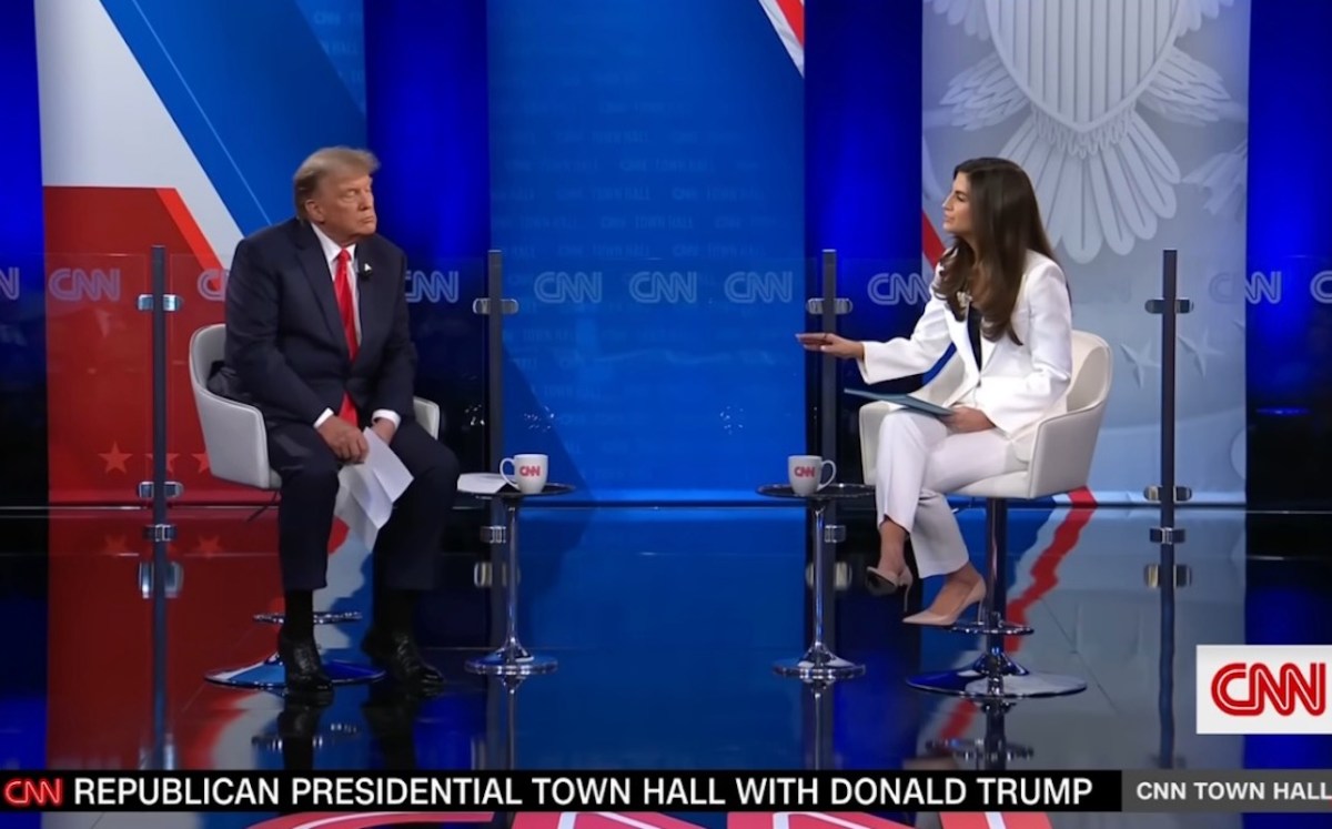 Kaitlan Collins wears a white suit while interviewing Donald Trump on a stage.