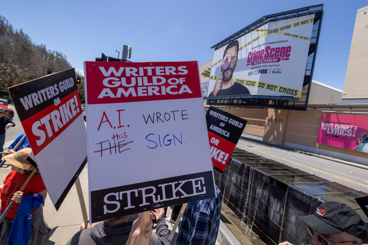 A picket sign in Los Angeles reads, "Writers Guild of America Strike! A.I. wrote the sign." "The" is crossed out with "this" written above it.