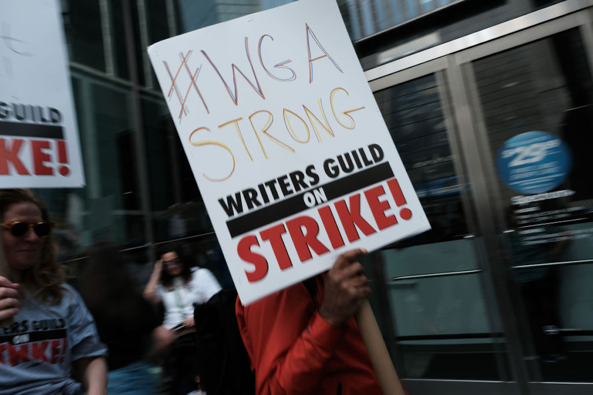A picketer holds a sign reading "#WGA Strong"
